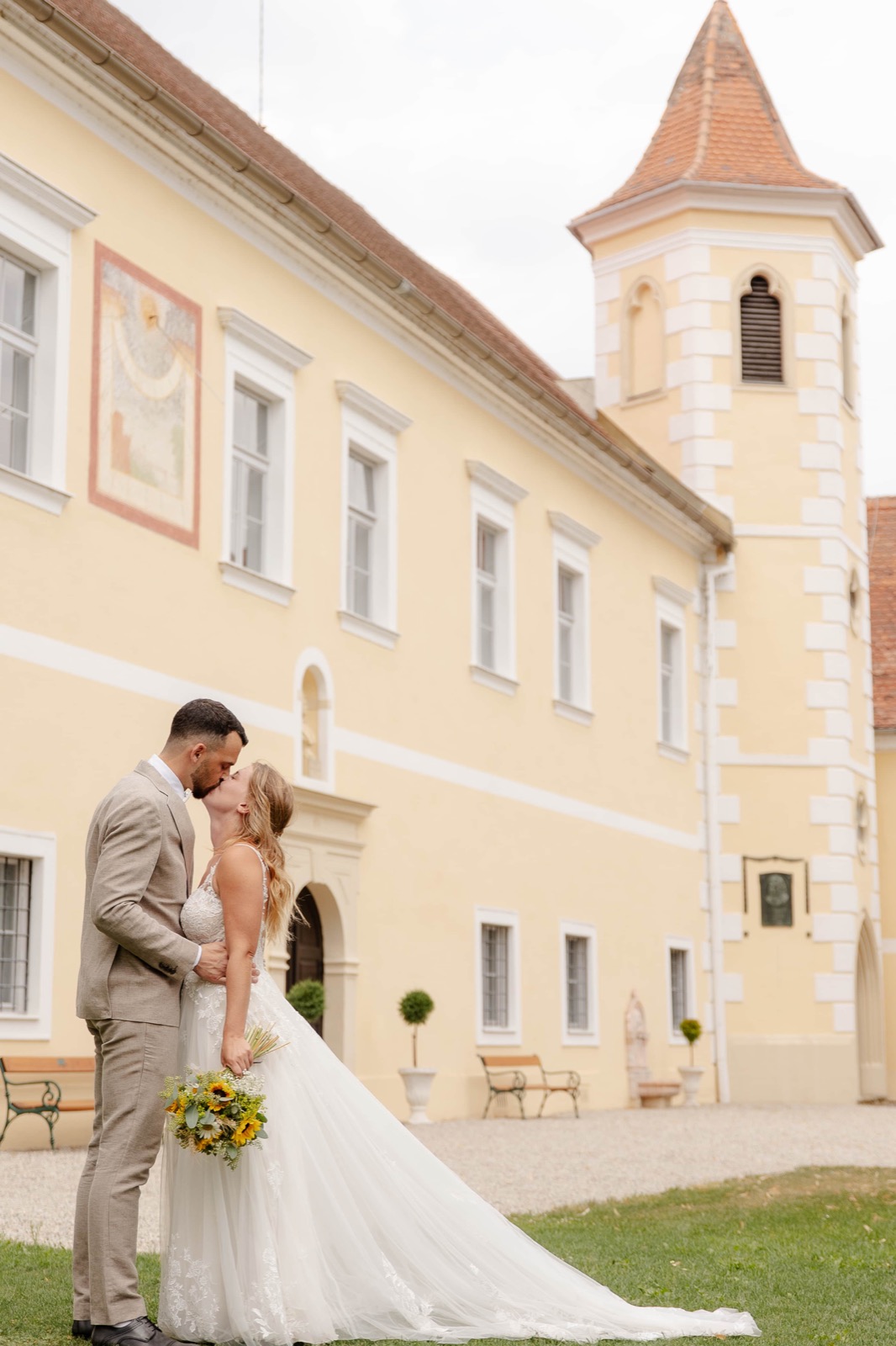 Brautpaar küsst sich vor dem gelben Schloss