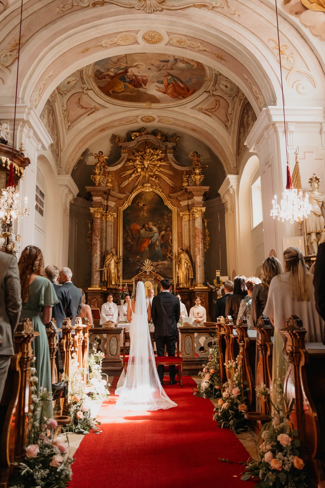 Blick durch die barocke Kirche zum Brautpaar am Altar während der Trauung