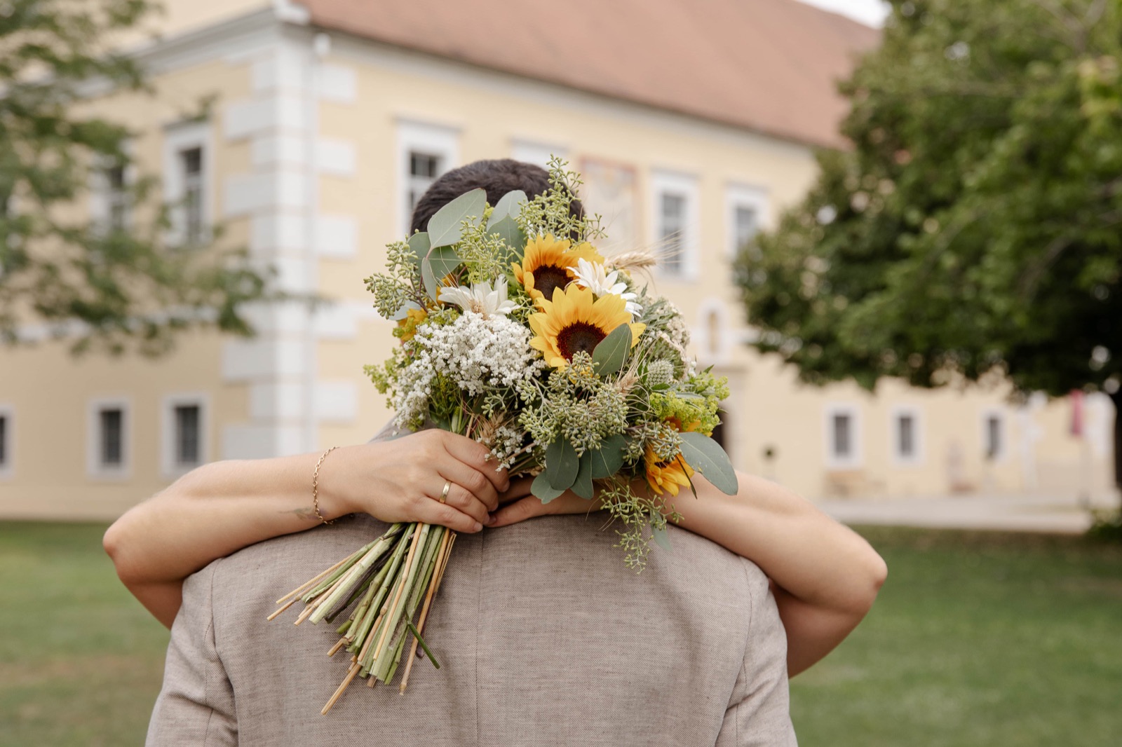 Sonnenblumen-Brautstrauß über der Schulter des Bräutigams